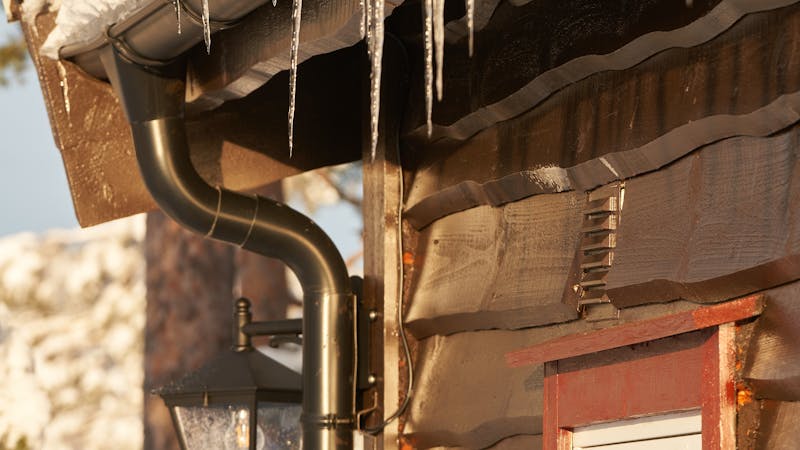 Nettoyage de gouttières sur une toiture enneigée contre les barrages de glace